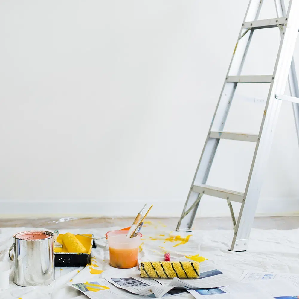 Painting-Equipment-On-The-Floor-SQ-1.webp Commercial Painting equipment on a drop sheet including a paint roller, brushes, paint can and a ladder