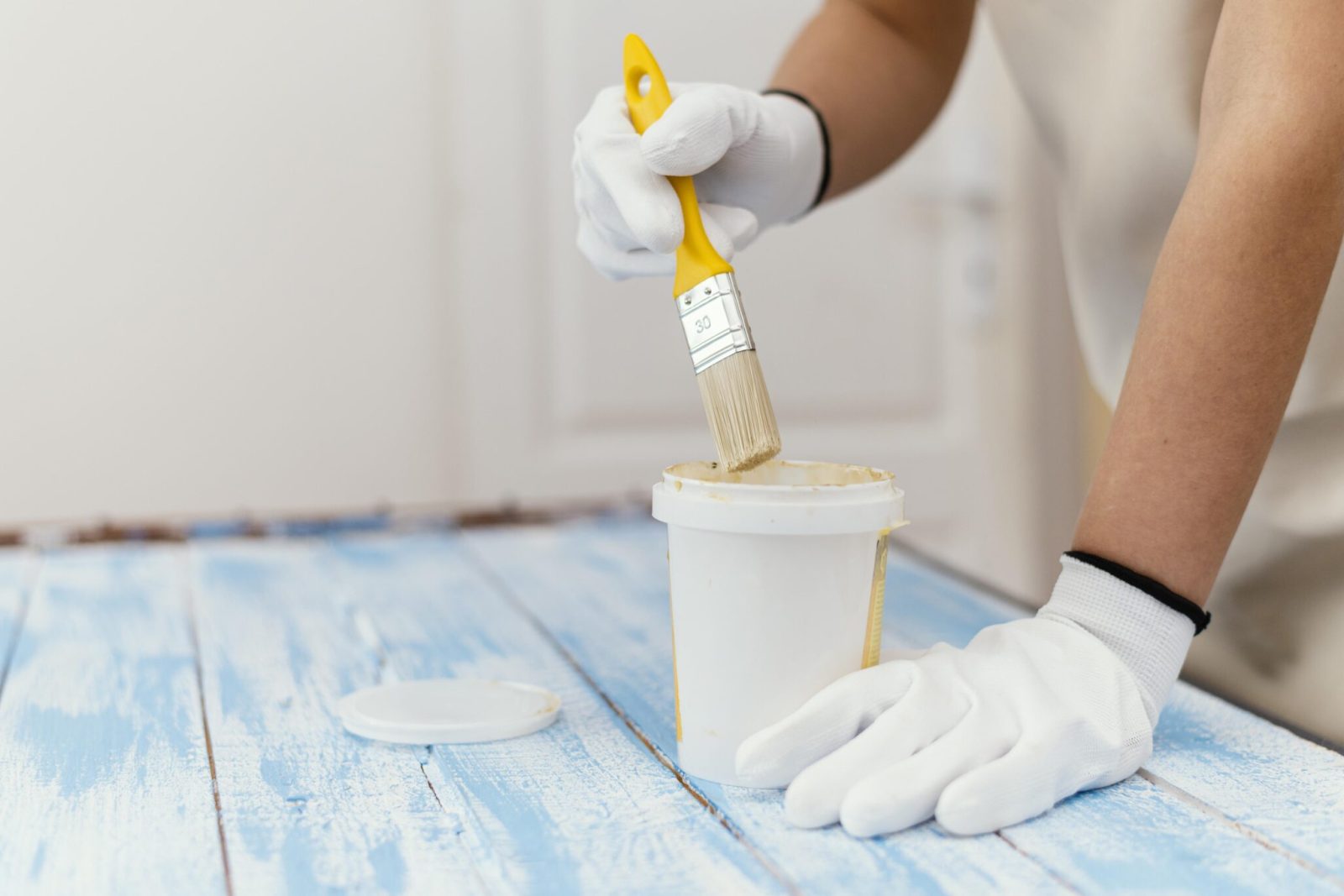 young-businesswoman-owner-working-LS-scaled-1.jpg A close up of a painter using a brush to seal a paint distressed blue wooden panel